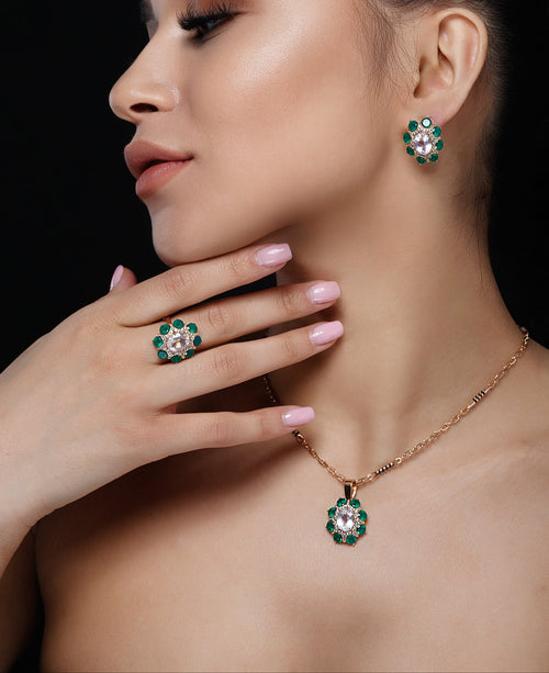 Woman wearing emerald green jewelry including earrings, ring, and necklace on a black background